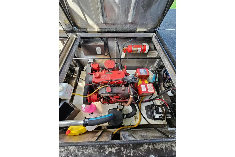 Slide: The Image of Engine compartment of a 2002 Jamestowner houseboat, featuring a red engine and fire extinguisher. - 50
