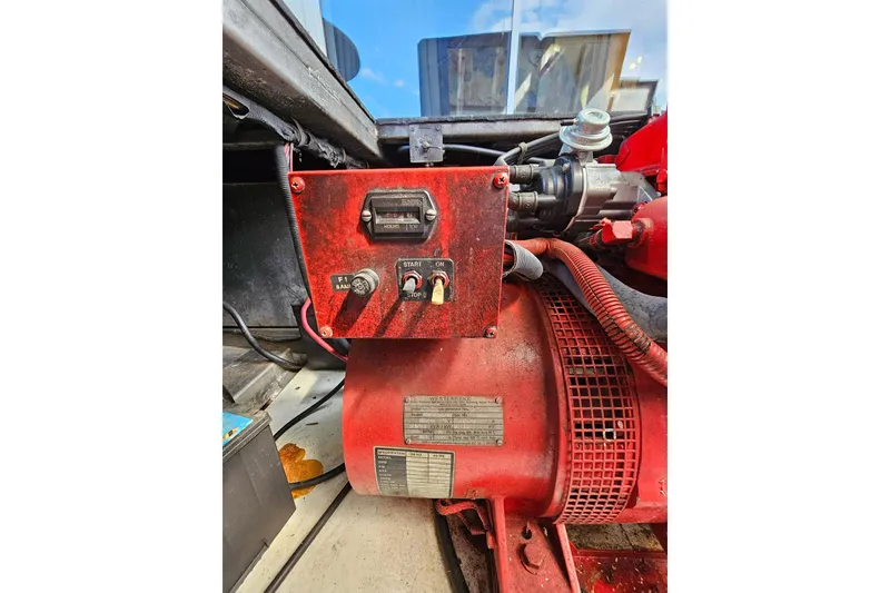 Slide: The Image of Red engine compartment of a 2002 Jamestowner houseboat, featuring control switches and wiring. - 51