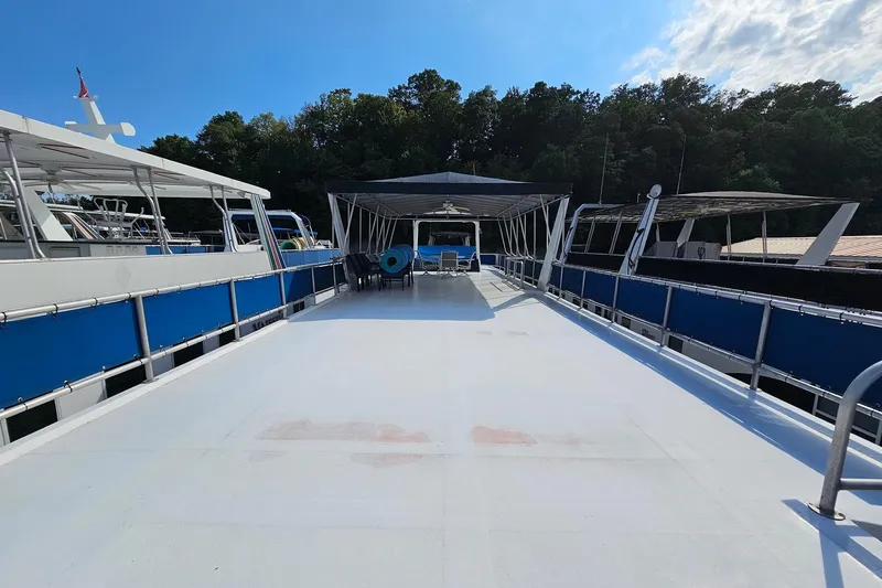 Slide: The Image of 2002 Jamestowner houseboat deck with blue railings, docked near lush green trees. - 7