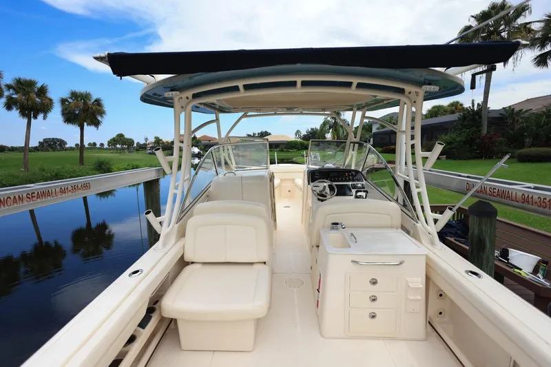 Slide: The Image of 2018 Grady-White Freedom 285 boat interior with seating and console, docked by a canal. - 11