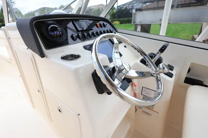 Slide: The Image of 2018 Grady-White Freedom 285 boat dashboard with steering wheel and controls. - 18