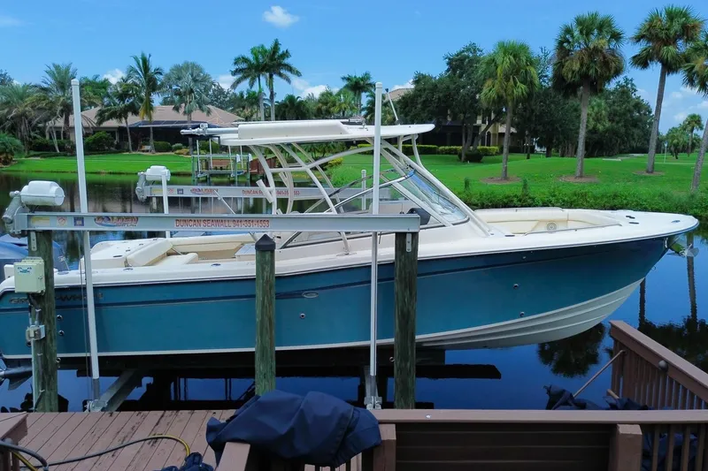 Slide: The Image of 2018 Grady-White Freedom 285 boat docked by a scenic waterfront with palm trees. - 2