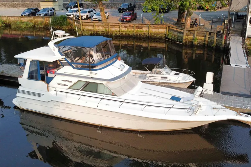 Slide: The Image of 1990 Sea Ray 440 Aft Cabin yacht docked in a serene marina setting. - 0