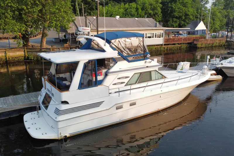 Slide: The Image of 1990 Sea Ray 440 Aft Cabin yacht docked at a marina, surrounded by lush greenery. - 1