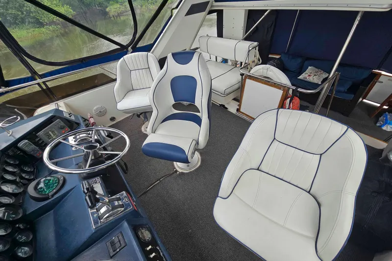 Slide: The Image of 1990 Sea Ray 440 Aft Cabin interior with helm, white and blue seating. - 11