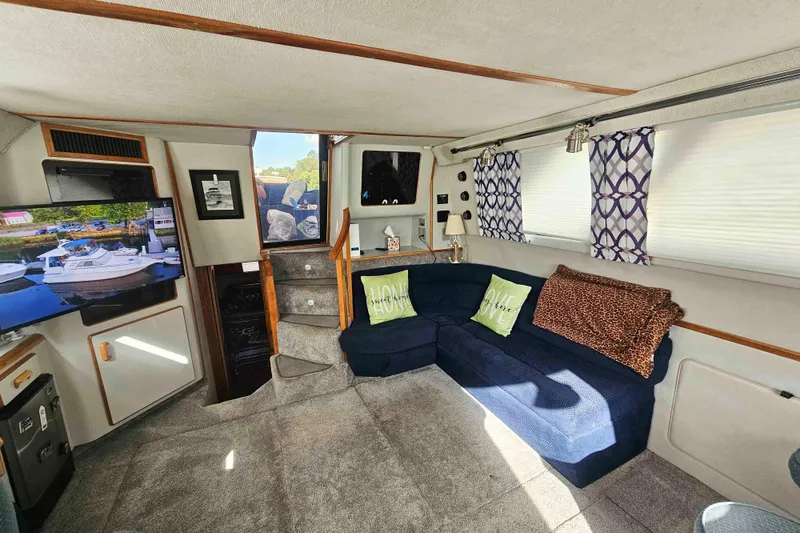 Slide: The Image of 1990 Sea Ray 440 Aft Cabin interior with cozy seating, TV, and nautical decor. - 16