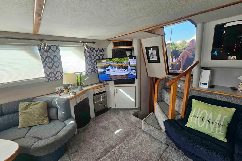 Slide: The Image of 1990 Sea Ray 440 Aft Cabin interior with cozy seating, TV, and decorative accents. - 19