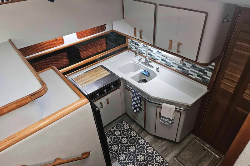 Slide: The Image of 1990 Sea Ray 440 Aft Cabin kitchen with modern design, wood accents, and patterned flooring. - 20
