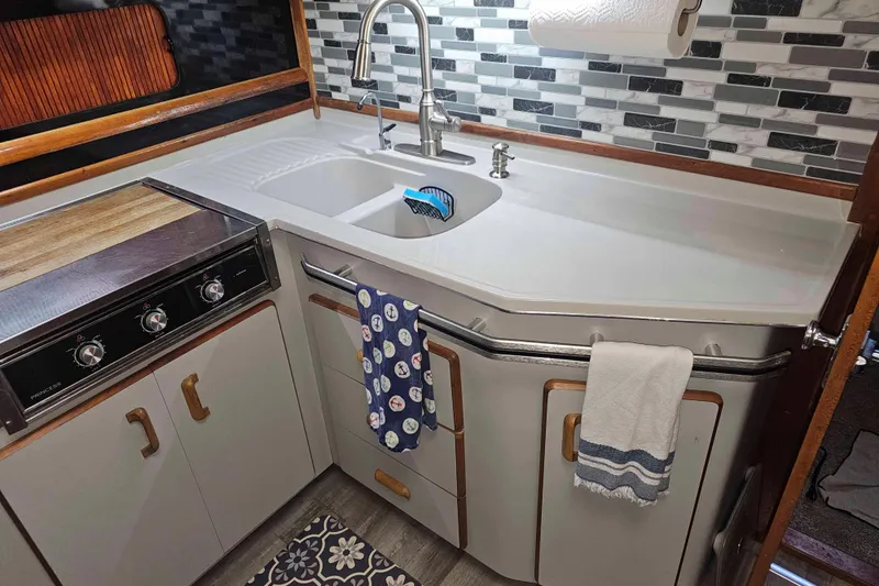 Slide: The Image of 1990 Sea Ray 440 Aft Cabin kitchen with modern sink, stove, and backsplash. - 21