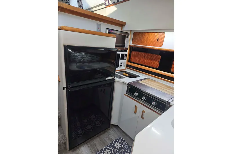 Slide: The Image of 1990 Sea Ray 440 Aft Cabin kitchen with fridge, stove, and wooden cabinets. - 22