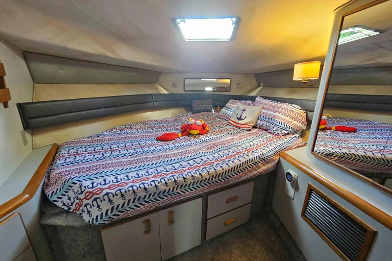 Slide: The Image of Cozy cabin interior of 1990 Sea Ray 440 Aft, featuring nautical-themed bedding. - 27