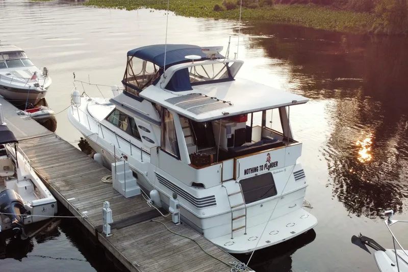 Slide: The Image of 1990 Sea Ray 440 Aft Cabin yacht docked at sunset, reflecting on calm water. - 3