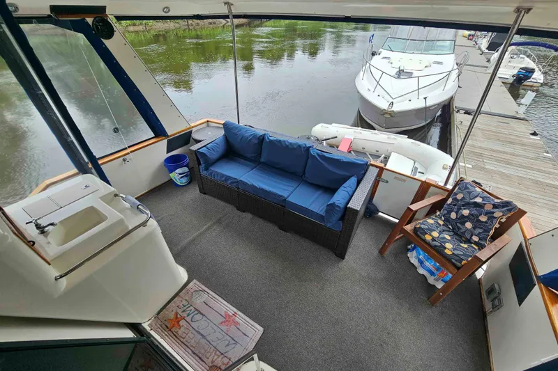 Slide: The Image of 1990 Sea Ray 440 Aft Cabin yacht interior with blue seating, docked by the water. - 4