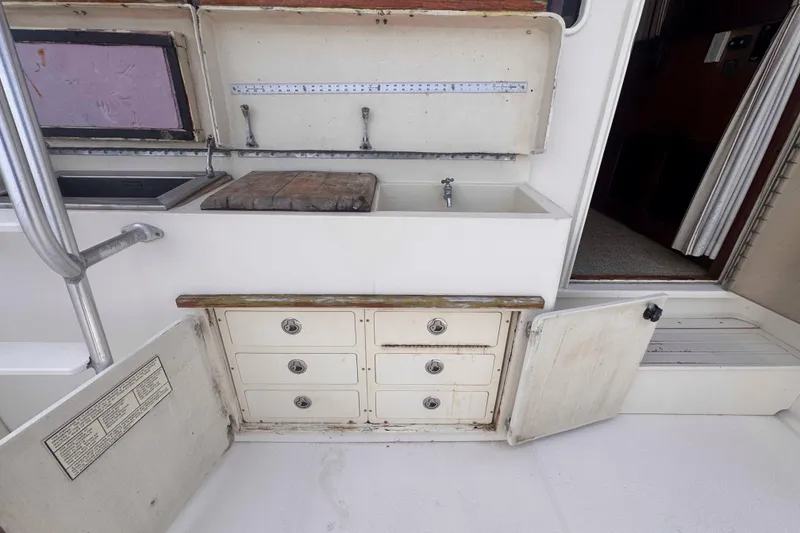 Slide: The Image of 1987 Chris-Craft 422 Commander boat interior with sink, storage drawers, and open cabinet. - 12