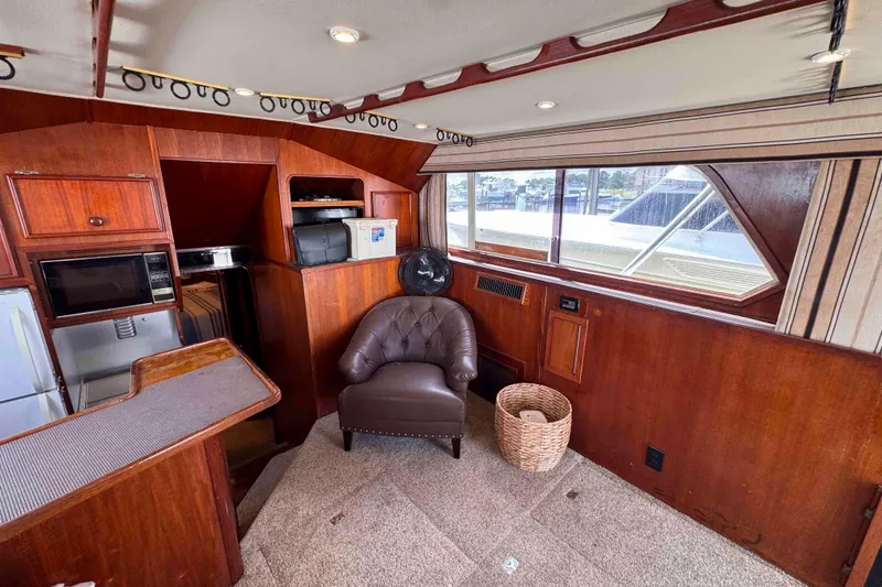 Slide: The Image of 1987 Chris-Craft 422 Commander interior with wood paneling, leather chair, and kitchenette. - 19