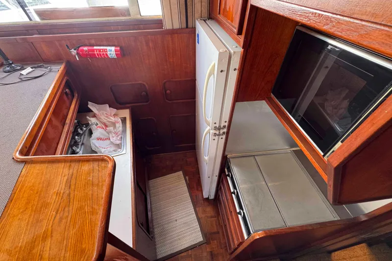 Slide: The Image of 1987 Chris-Craft 422 Commander kitchen with wood cabinetry, sink, fridge, and microwave. - 21