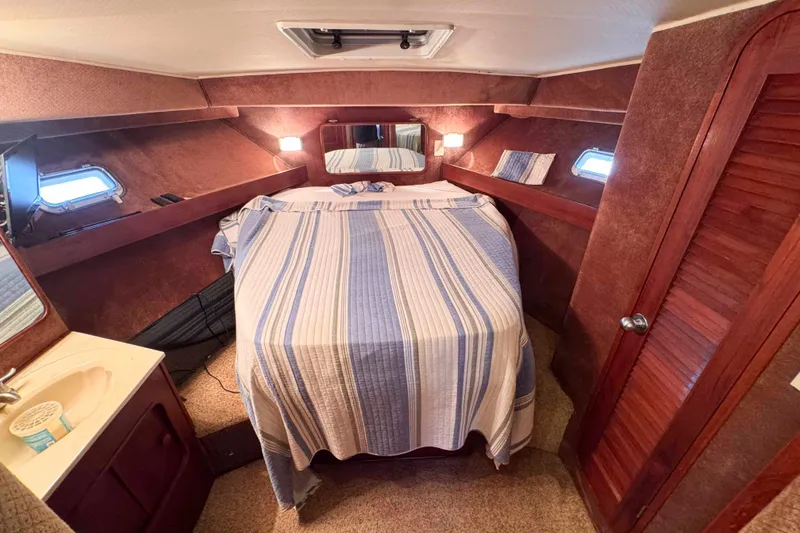 Slide: The Image of Cozy cabin interior of 1987 Chris-Craft 422 Commander with striped bedding and wooden accents. - 25
