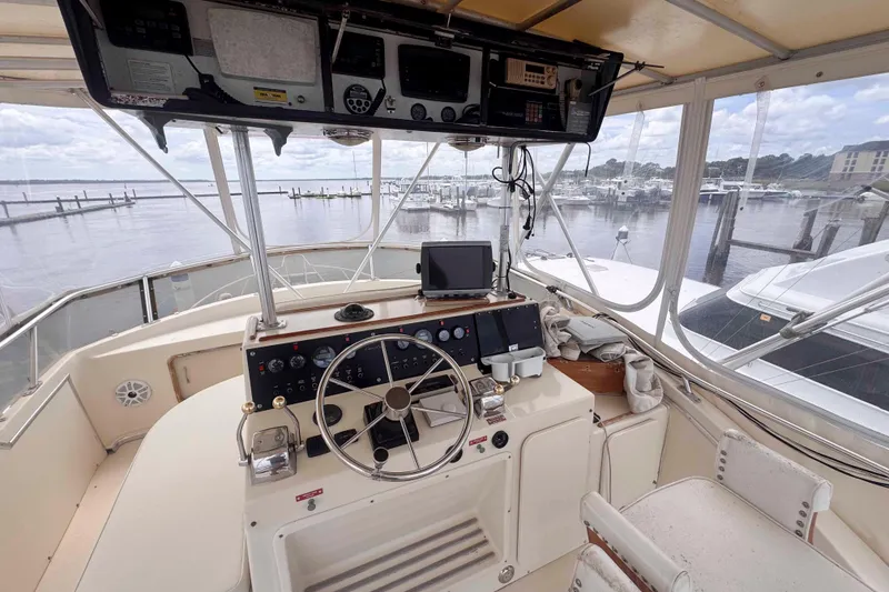 Slide: The Image of 1987 Chris-Craft 422 Commander helm with steering wheel, navigation equipment, and marina view. - 4