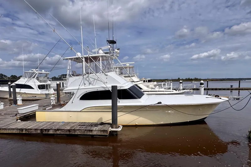 The Image of 1989 Buddy Davis 47 yacht docked at marina under cloudy sky. - 0