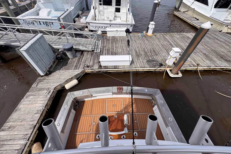 Slide: The Image of 1989 Buddy Davis 47 boat docked at marina with wooden deck and fishing rods. - 15