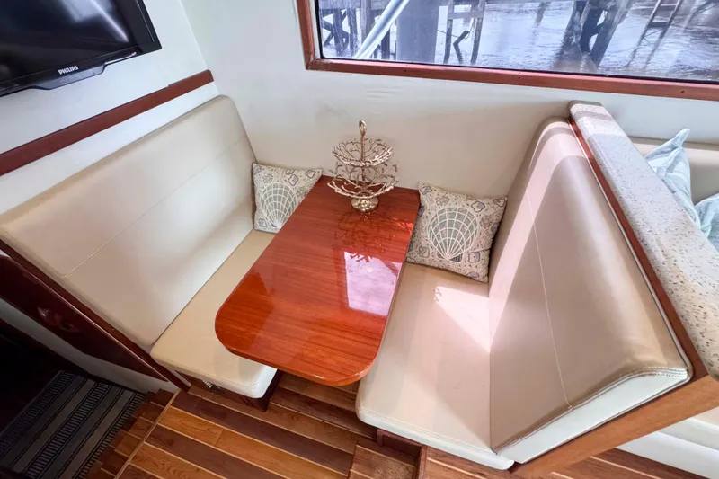 Slide: The Image of Cozy dining area on 1989 Buddy Davis 47 yacht with elegant wood table and cushioned seating. - 24