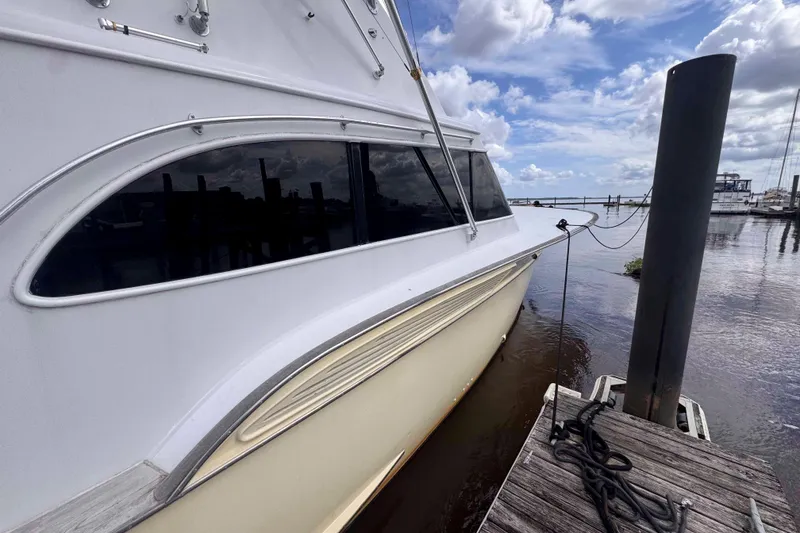 Slide: The Image of 1989 Buddy Davis 47 yacht docked, showcasing sleek design and reflective windows under a cloudy sky. - 3