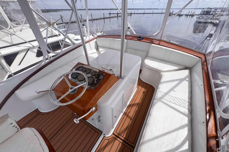 Slide: The Image of 1989 Buddy Davis 47 yacht helm with wooden accents and white seating, docked at marina. - 6