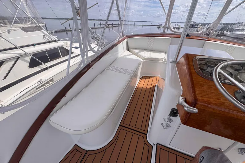 Slide: The Image of 1989 Buddy Davis 47 yacht interior with white seating and wooden helm, docked at marina. - 8