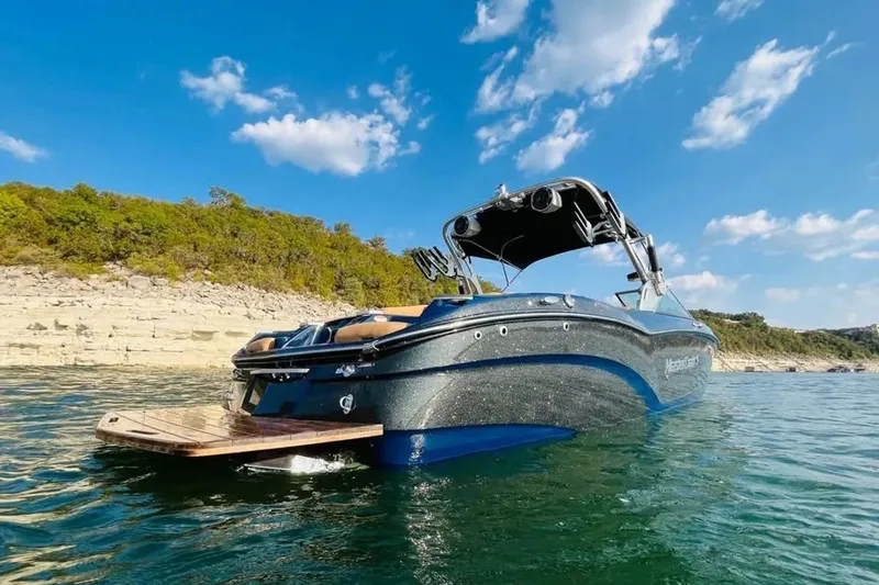 Slide: The Image of 2019 MasterCraft X26 boat on a sunny lake with clear blue skies. - 4