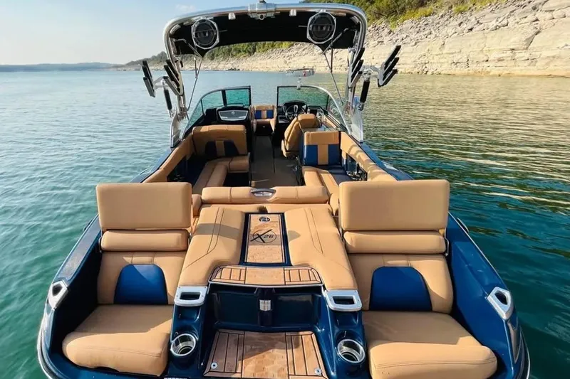 Slide: The Image of Luxurious 2019 MasterCraft X26 boat interior with tan seating on a serene lake. - 8