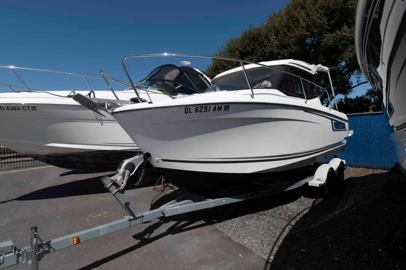 Slide: The Image of 2020 Jeanneau NC 695 boat on trailer, parked outdoors under clear blue sky. - 0