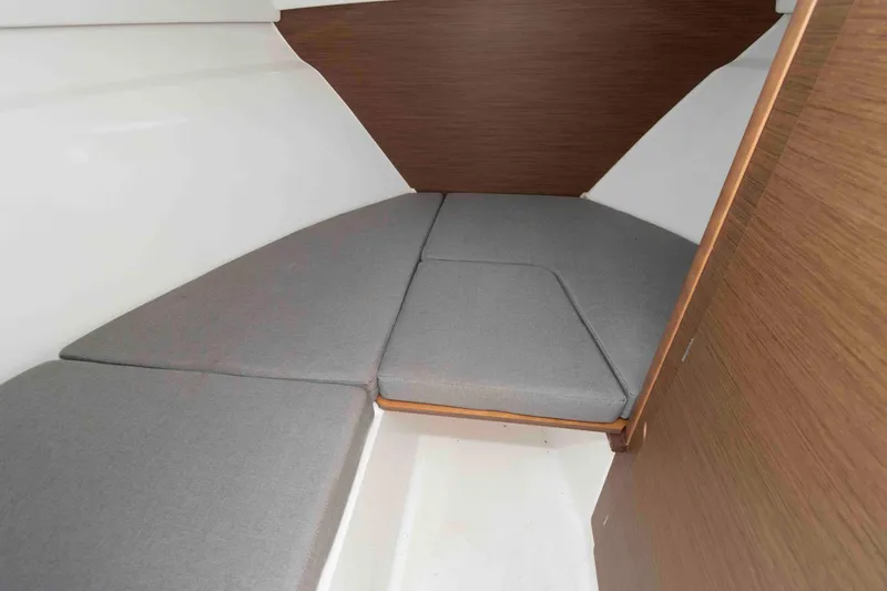 Slide: The Image of 2020 Jeanneau NC 695 interior cabin with gray cushions and wooden accents. - 10