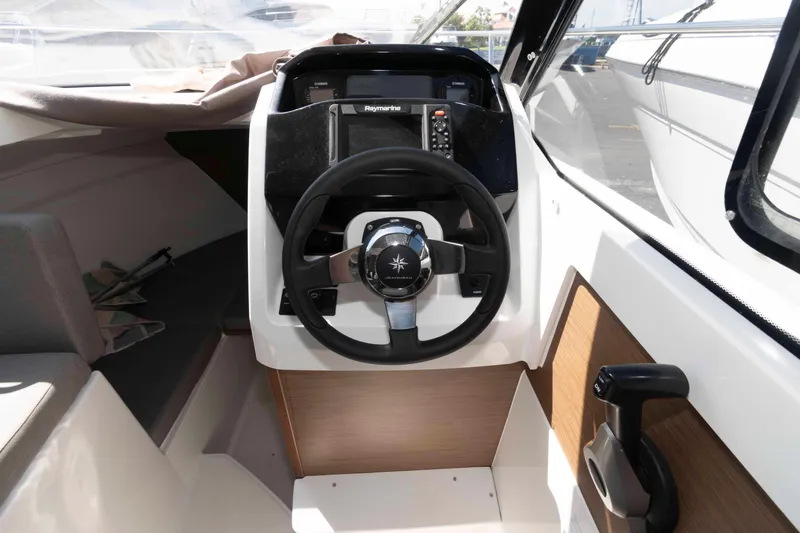 Slide: The Image of 2020 Jeanneau NC 695 boat cockpit with steering wheel and navigation controls. - 6