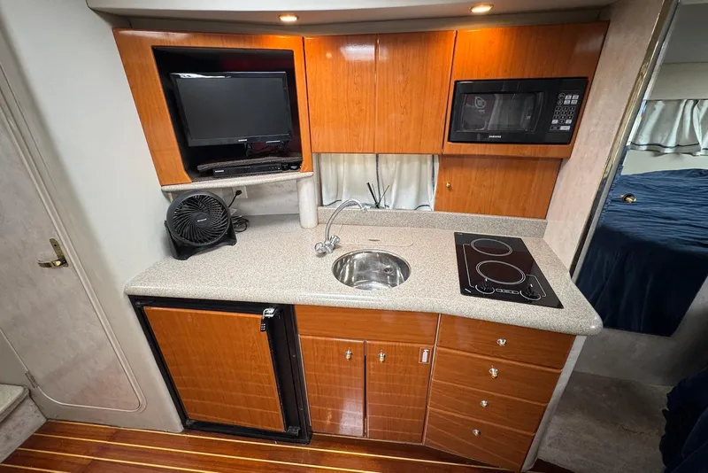 Slide: The Image of 2002 Formula 37 Performance Cruiser kitchen with sink, stove, microwave, and TV. - 14