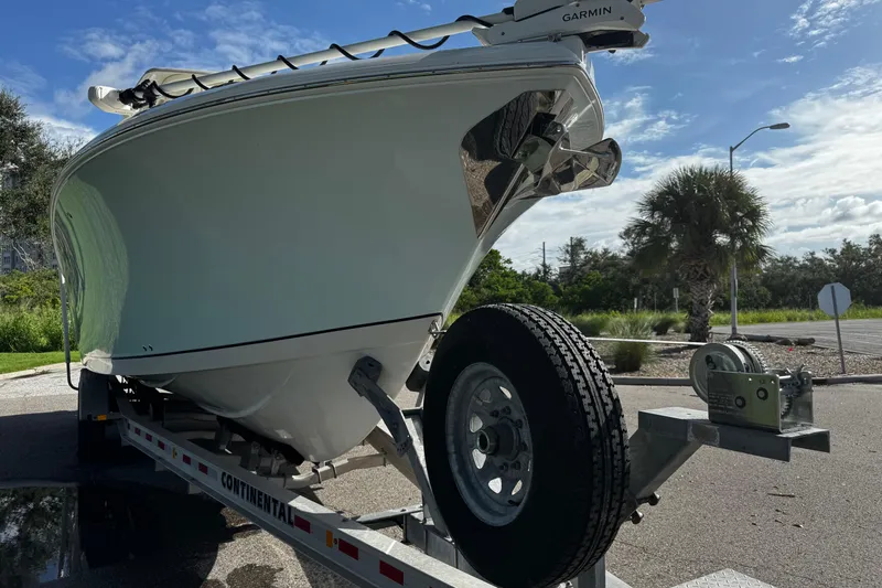 Slide: The Image of 2015 Sailfish 320 CC boat on trailer, parked outdoors under a clear blue sky. - 10