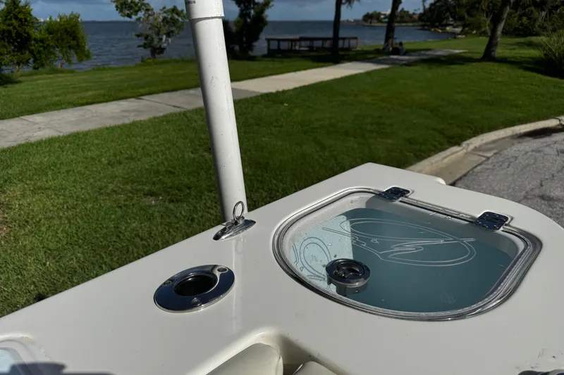Slide: The Image of 2015 Sailfish 320 CC boat detail with rod holder and livewell, near a scenic waterfront. - 16