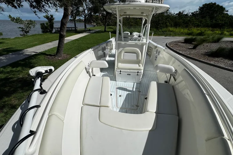Slide: The Image of 2015 Sailfish 320 CC boat with white interior, docked near a scenic lakeside path. - 27