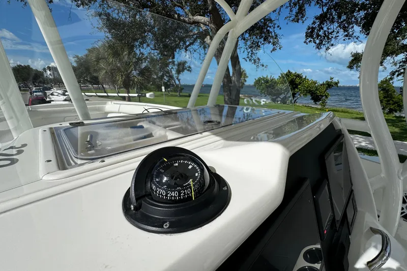 Slide: The Image of 2015 Sailfish 320 CC boat cockpit with compass, overlooking a scenic waterfront view. - 36