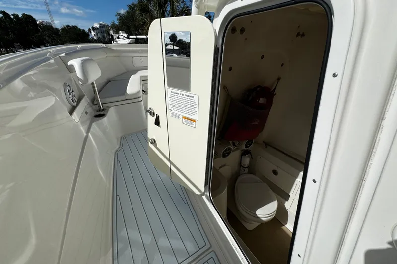 Slide: The Image of 2015 Sailfish 320 CC boat interior with open door revealing compact bathroom. - 42
