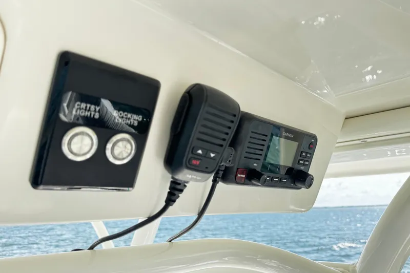 Slide: The Image of 2015 Sailfish 320 CC boat dashboard with Garmin radio and light controls. - 56