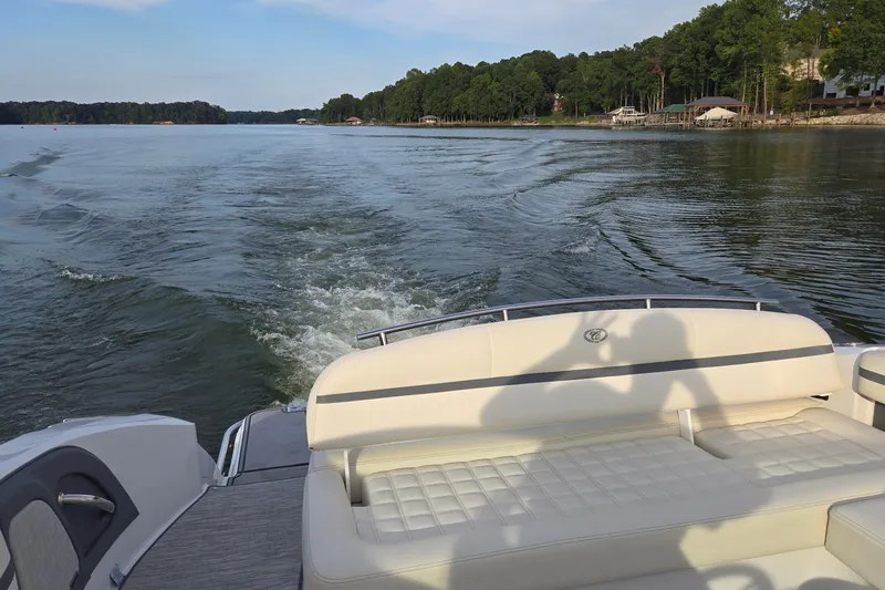 Slide: The Image of 2021 Cobalt R5 boat cruising on a serene lake with lush green shoreline. - 20