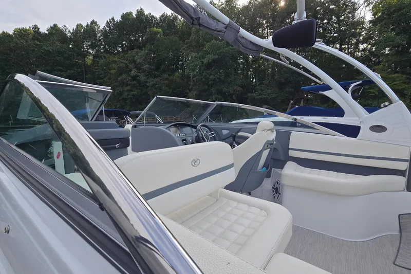 Slide: The Image of 2021 Cobalt R5 boat interior with white seating and sleek design, surrounded by trees. - 22