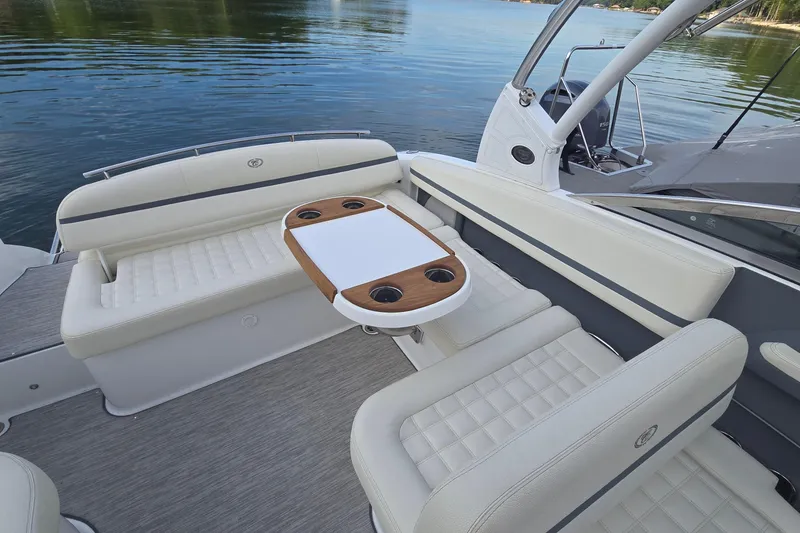 Slide: The Image of 2021 Cobalt R5 boat interior with white seating and wooden table on calm water. - 31
