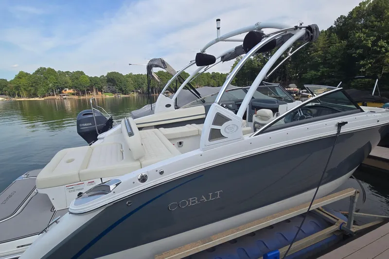 Slide: The Image of 2021 Cobalt R5 boat docked on a serene lake with lush green surroundings. - 5