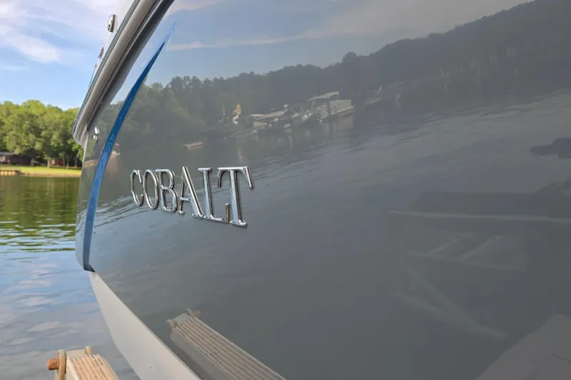 Slide: The Image of 2021 Cobalt R5 boat on a serene lake with docked boats in the background. - 8
