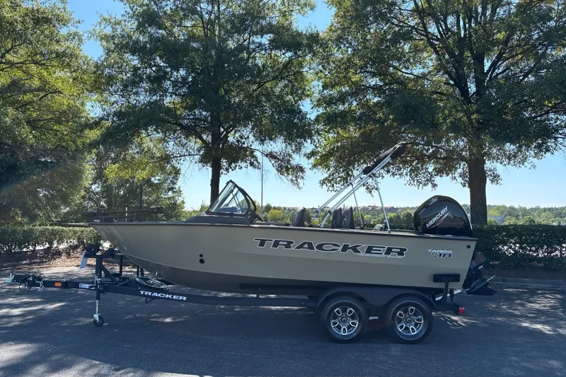 Slide: The Image of 2026 Tracker Targa V-18 Combo boat on trailer, parked under trees. - 2