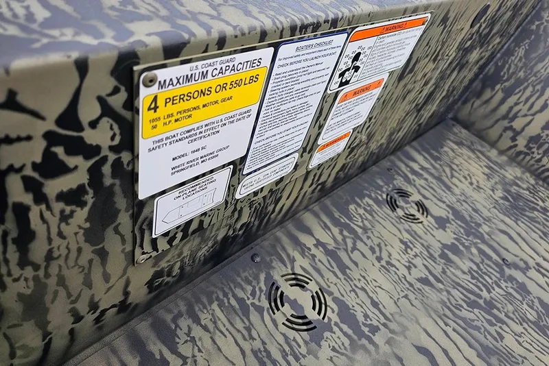 Slide: The Image of 2026 Tracker Grizzly 1648 SC boat capacity and safety labels on camouflage interior. - 14