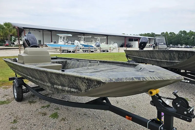 Slide: The Image of 2026 Tracker Grizzly 1648 SC boat on trailer, parked outdoors near a showroom. - 5