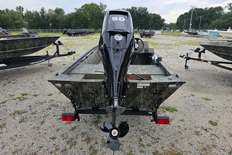 Slide: The Image of 2026 Tracker Grizzly 1648 SC boat with outboard motor, parked on gravel lot. - 8