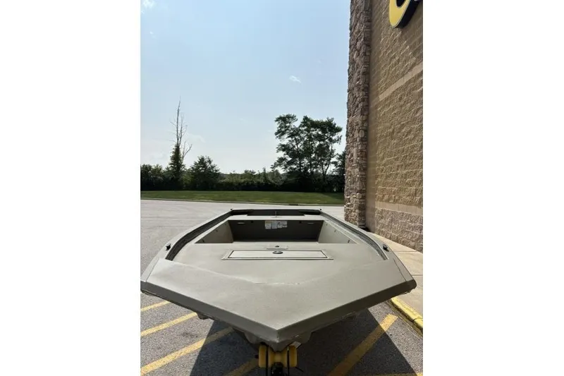 Slide: The Image of 2026 Tracker Grizzly 1648 Utility boat parked outdoors near a building. - 2